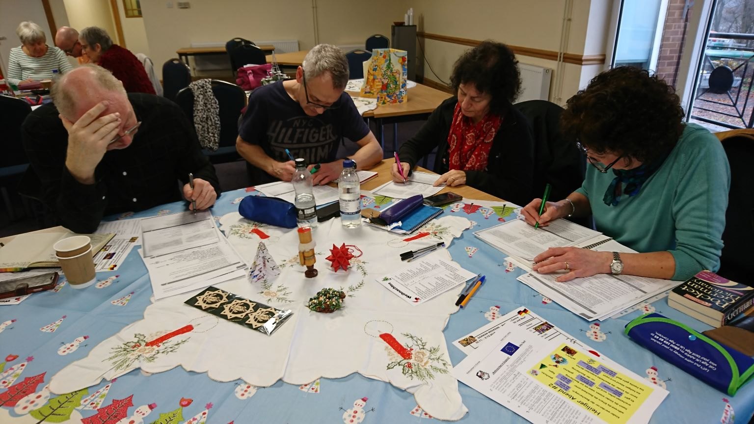 Learners working on German exercises around a table in one of Christiane’s courses